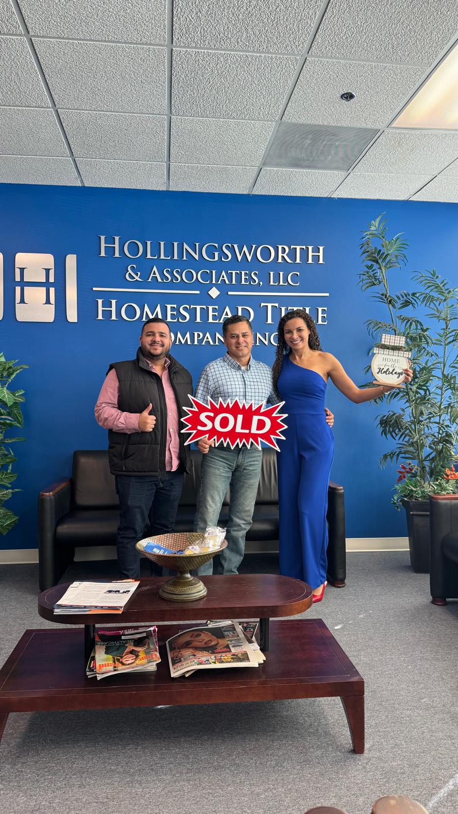 Dos clientes celebrando con el cartel de vendido en el cierre de su casa